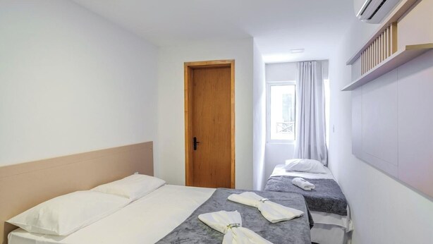 Ett hotellrum med två sängar, en trädörr och ett fönster med gardiner.