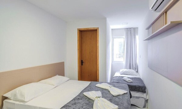 Een hotelkamer met twee bedden, een houten deur en een raam met gordijnen.