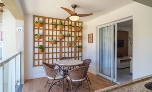 A balcony with wicker furniture, a ceiling fan, and a wooden lattice wall with hanging planters. - Equipped apt in Cond. w/ Pool - Imbassai Itfa039 (Mata de São João)