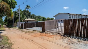A gated property with a dirt road leading to a building with a tiled roof.