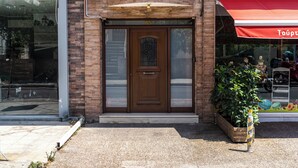 A building entrance with a brick facade, a wooden door, and a small planter with green plants.