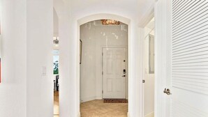 A hallway with a white door, wooden flooring, and a patterned rug.