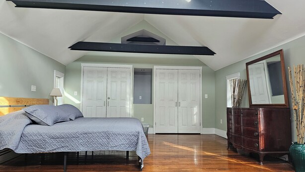 A bedroom with a bed, dresser, wardrobe, and a large mirror. - Discreet 1 Bedroom getaway (Buffalo)