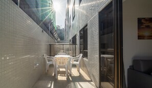 A narrow outdoor patio with a table and chairs, a glass door, and a tiled wall. - Apt in Condo one Block From the sea w Pool Hss0007 (João Pessoa)