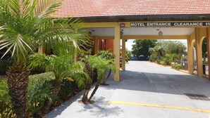 A motel entrance with a red-tiled roof and a sign indicating clearance. - Budget Inn - Orlando Downtown (Orlando)