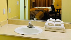 A hotel bathroom with a sink, mirror, and towels. - Budget Inn - Orlando Downtown (Orlando)