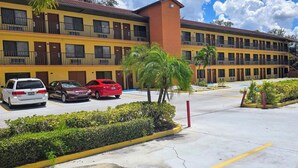 A multi-story motel with a yellow facade, multiple balconies, and a parking lot with several cars. - Budget Inn - Orlando Downtown (Orlando)