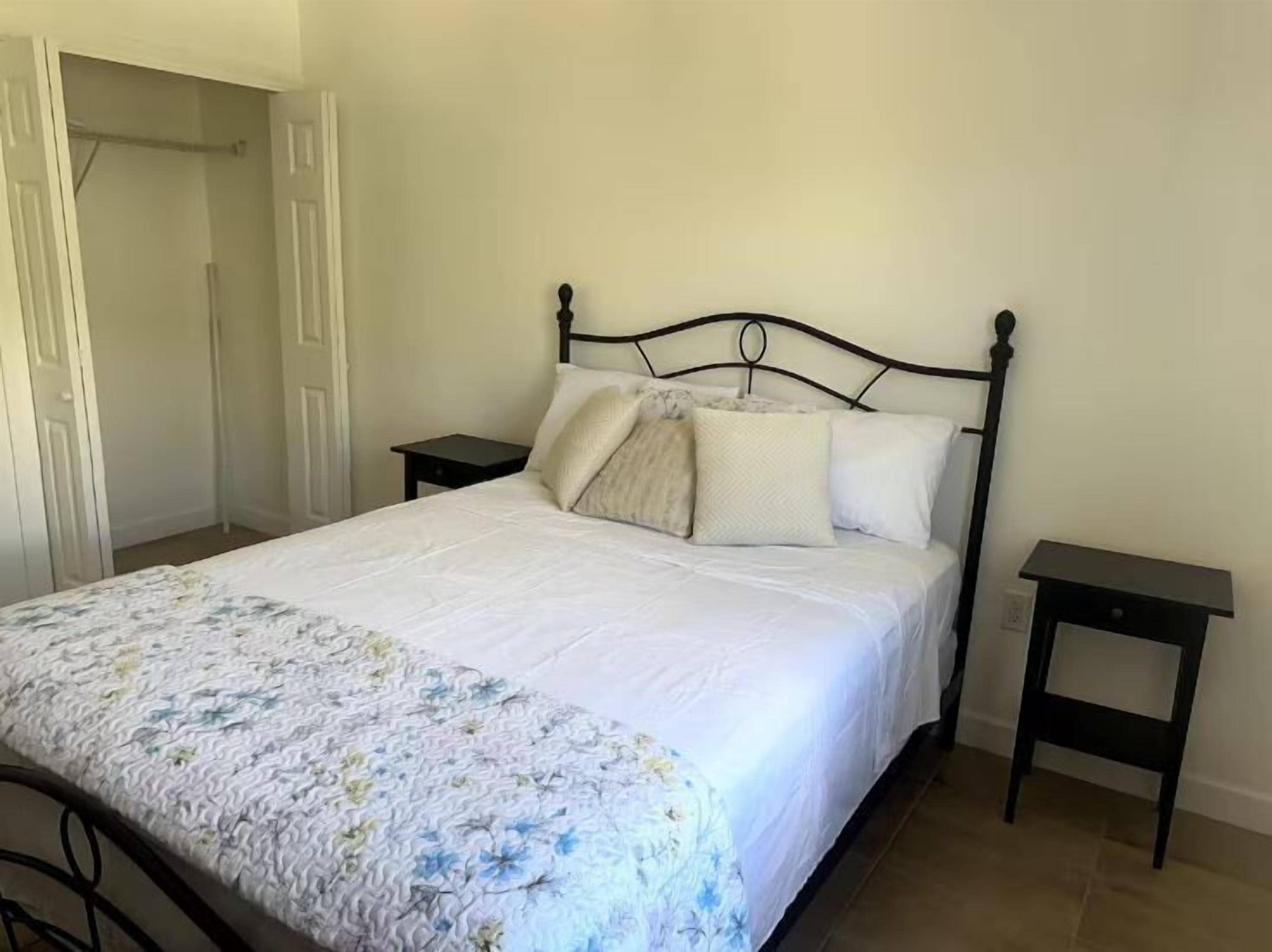Un dormitorio con cama, mesita de noche y una puerta.