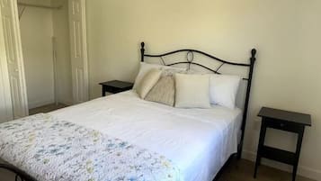 Un dormitorio con cama, mesita de noche y una puerta.