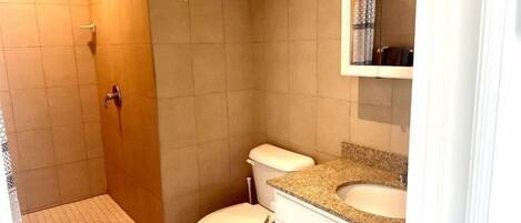 A bathroom with a shower, toilet, and vanity.