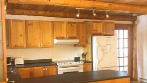 A rustic kitchen with wooden cabinets, a central island, and a stove.