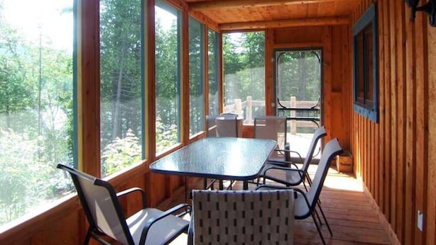 A wooden cabin with a glass-enclosed dining area, a table, and chairs.