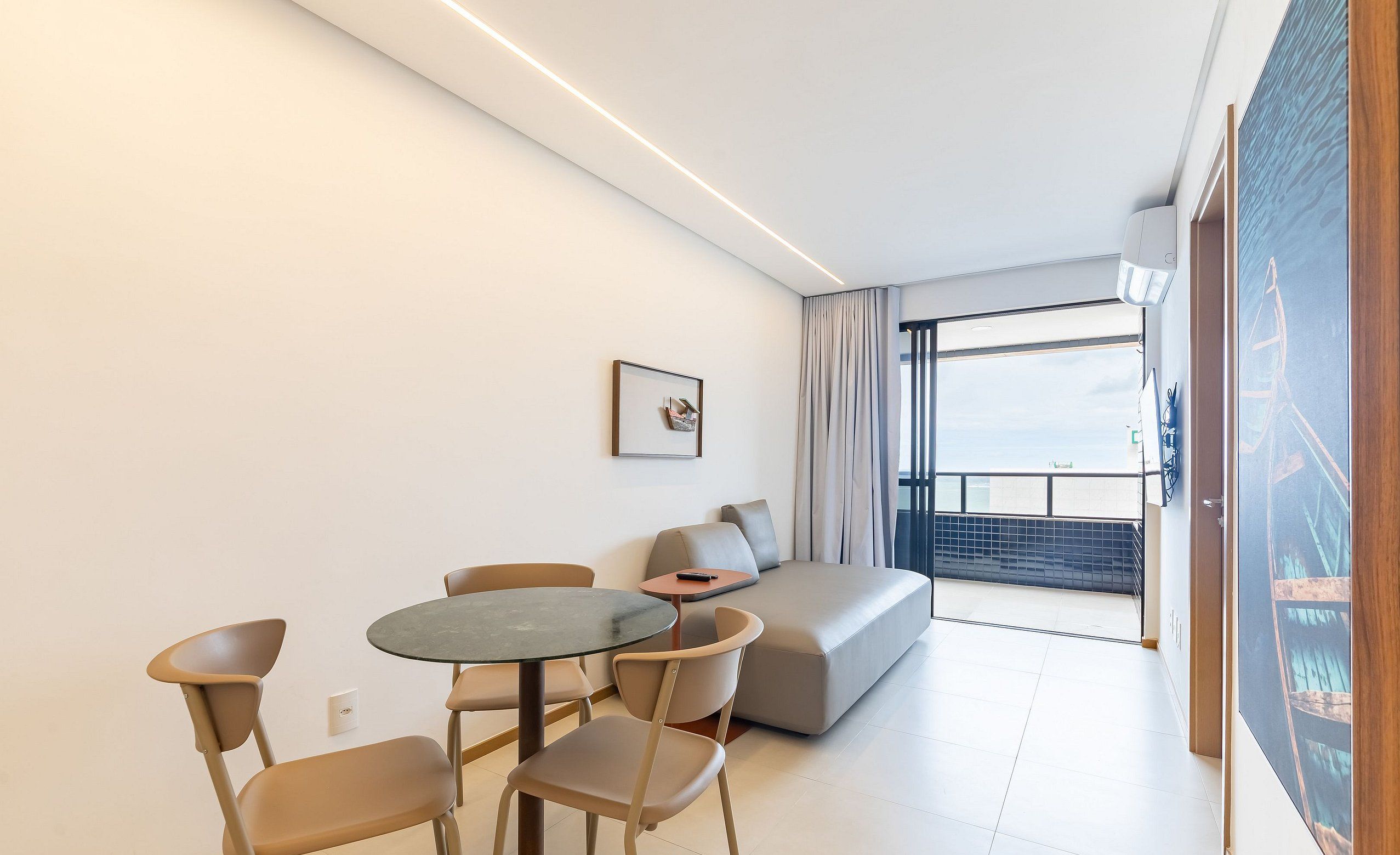A modern living room with a round table, two chairs, a sofa, and a large window with a view.