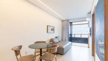 A modern living room with a round table, two chairs, a sofa, and a large window with a view.