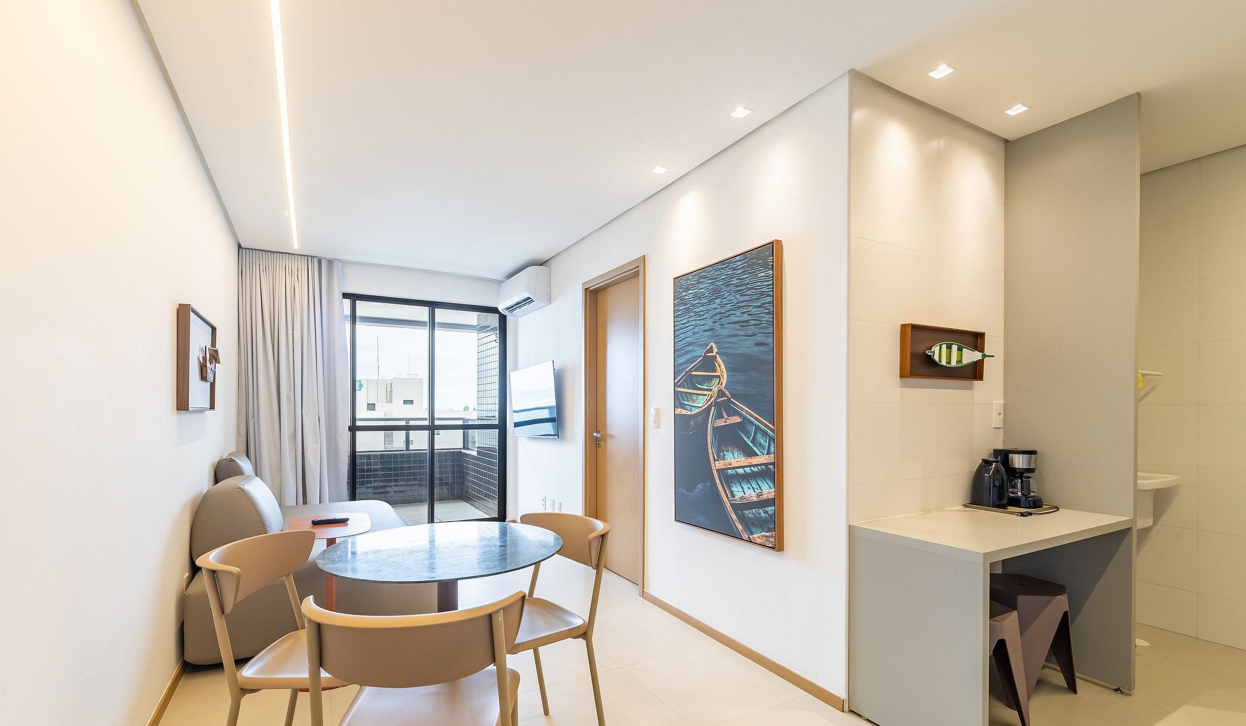 Una habitación de hotel moderna con zona de comedor, estación de café y obras de arte en las paredes.