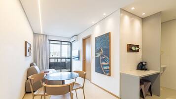 Una habitación de hotel moderna con zona de comedor, estación de café y obras de arte en las paredes.