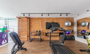 Uma academia em casa com esteira, banco de musculação e diversos equipamentos de ginástica.