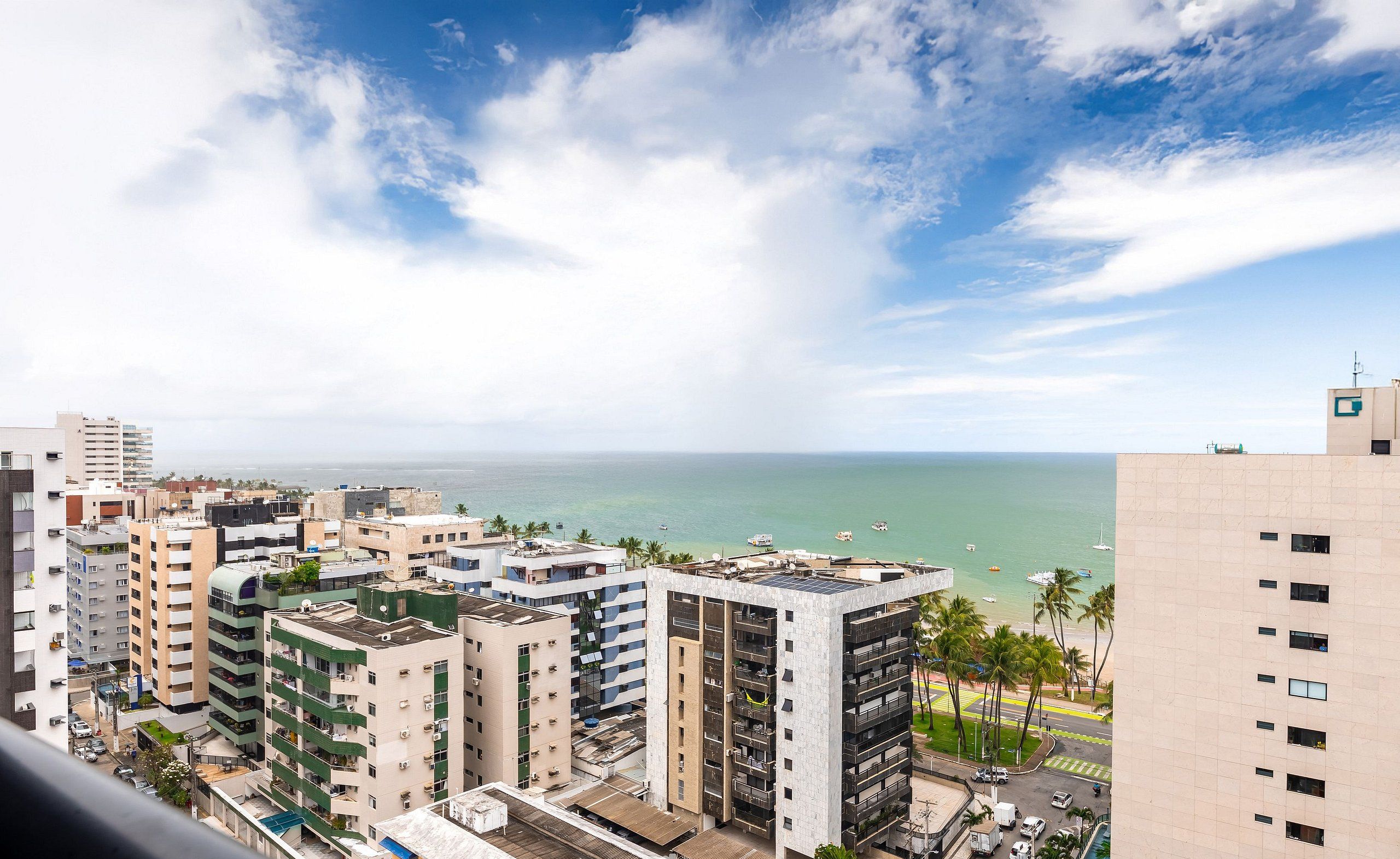 A high-rise building with multiple balconies overlooking a coastal area with a clear sky.
