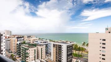 A high-rise building with multiple balconies overlooking a coastal area with a clear sky.