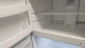 Tyhjä jääkaappi, jossa on useita hyllyjä ja erillinen pakastinosa.
