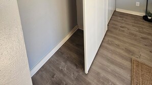 Huone, jossa on harmaa seinä, puulattia ja valkoinen kaappi liukuovella.