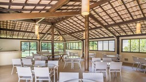 Un vaste espace intérieur doté de nombreuses tables et chaises, de grandes fenêtres et d’un plafond haut orné d’un motif en réseau.
