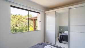 Une chambre à coucher avec un lit, une fenêtre et une porte coulissante donnant sur une salle de bain.