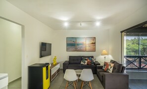 Una sala de estar moderna con un sofá, dos sillones, una mesa de centro, un televisor y obras de arte en la pared.