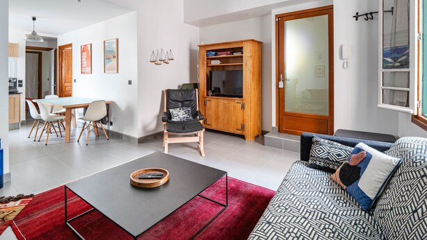 A modern living room with a sofa, a coffee table, and a dining area with chairs and a table. - Apartment 100m from the beach - historic center (Collioure)