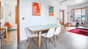 A modern living room with a sofa, a dining table with chairs, and a kitchen area. - Apartment 100m from the beach - historic center (Collioure)