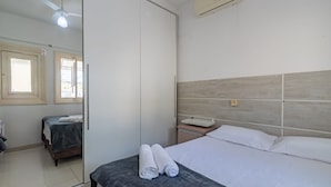 Una habitación de hotel con cama, mesita de noche, espejo y ventana.