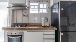 Una cocina con estufa a gas, horno, refrigerador y cafetera.