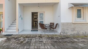 Un edificio de fachada blanca, con una escalera que lleva a una puerta y un patio con mesa y sillas.