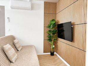 Un dormitorio moderno con una cama, un televisor de pared y una planta en maceta.