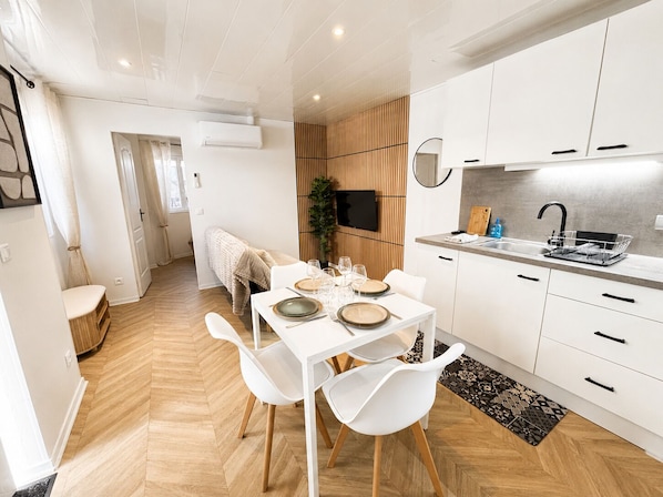 A modern kitchen with white cabinets, a built-in oven, and a countertop with a sink and dish rack.
