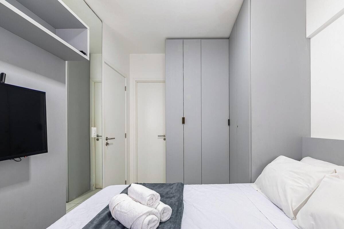 A hotel room with a bed, a TV, a wardrobe, and a mirror.