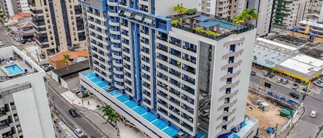 A high-rise building with multiple floors, balconies, and a swimming pool area.