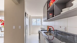 A modern kitchen with a black countertop, white cabinets, and a window providing natural light. - Apartments 450m From the Beach in Ilheus - ERN (Ilhéus)