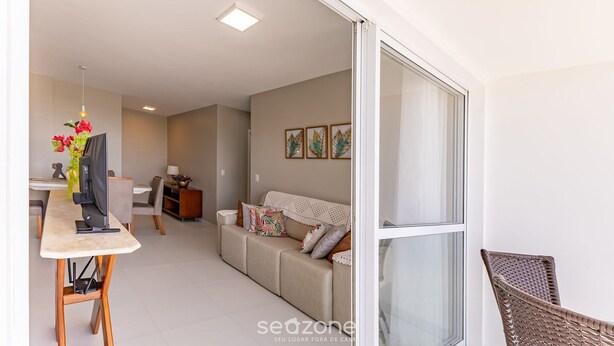 A modern living room with a sofa, a dining table with chairs, a TV, and a decorative vase. - Apartments 450m From the Beach in Ilheus - ERN (Ilhéus)