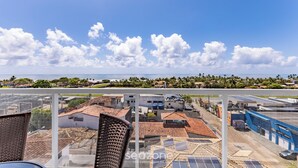 A balcony with a view of a coastal town, solar panels, and a clear blue sky. - Apartments 450m From the Beach in Ilheus - ERN (Ilhéus)