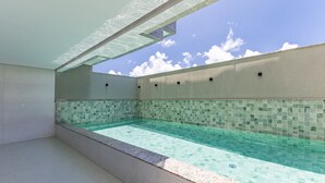 Piscina com borda azulejada e céu azul e límpido acima.