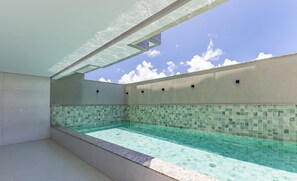 A swimming pool with a tiled edge and a clear blue sky above. - Apartments 450m From the Beach in Ilheus - ERN (Ilhéus)