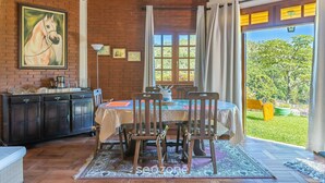 Un coin repas avec un mur en briques, un tableau représentant un cheval, une table en bois et des chaises.