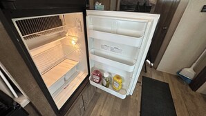 Un réfrigérateur ouvert, doté de plusieurs étagères et d’un compartiment congélateur.