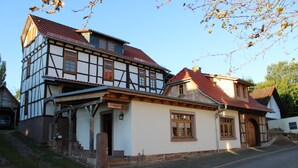 A traditional half-timbered house with a steeply pitched roof, a wooden front porch, and a sign indicating it is a restaurant. - Bohlenstube guest apartment (Birkenfelde)