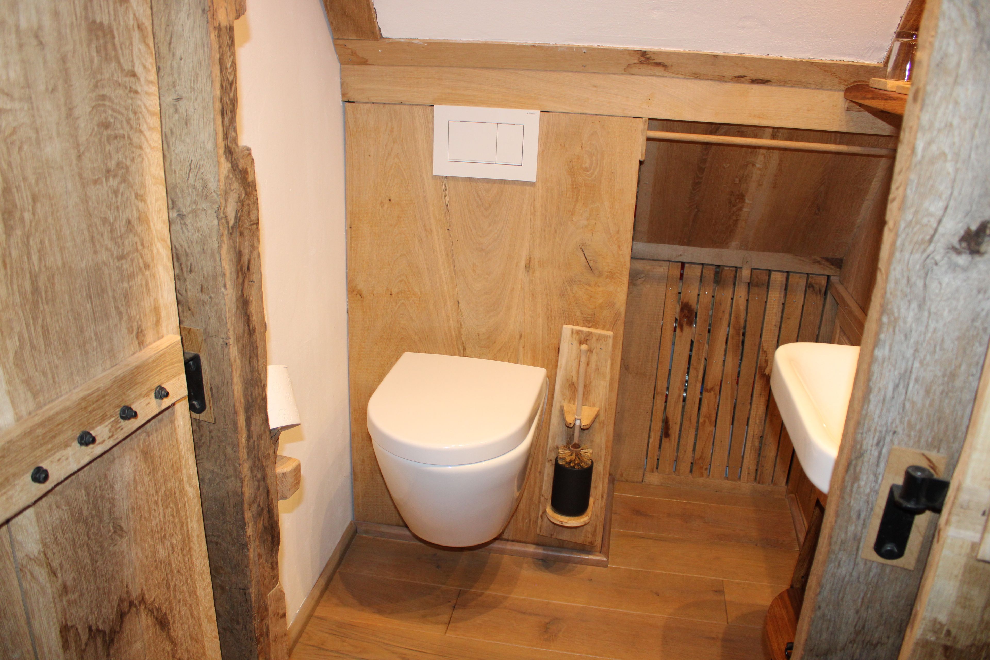 Un bany de fusta amb vàter, bidet i una porta de fusta.