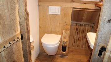 Un bany de fusta amb vàter, bidet i una porta de fusta.