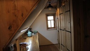 A small kitchen with wooden cabinets, a window, and a countertop with various kitchen items. - Bohlenstube guest apartment (Birkenfelde)