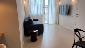 Uma sala de estar moderna com um sofá, uma mesinha e uma televisão fixada na parede.