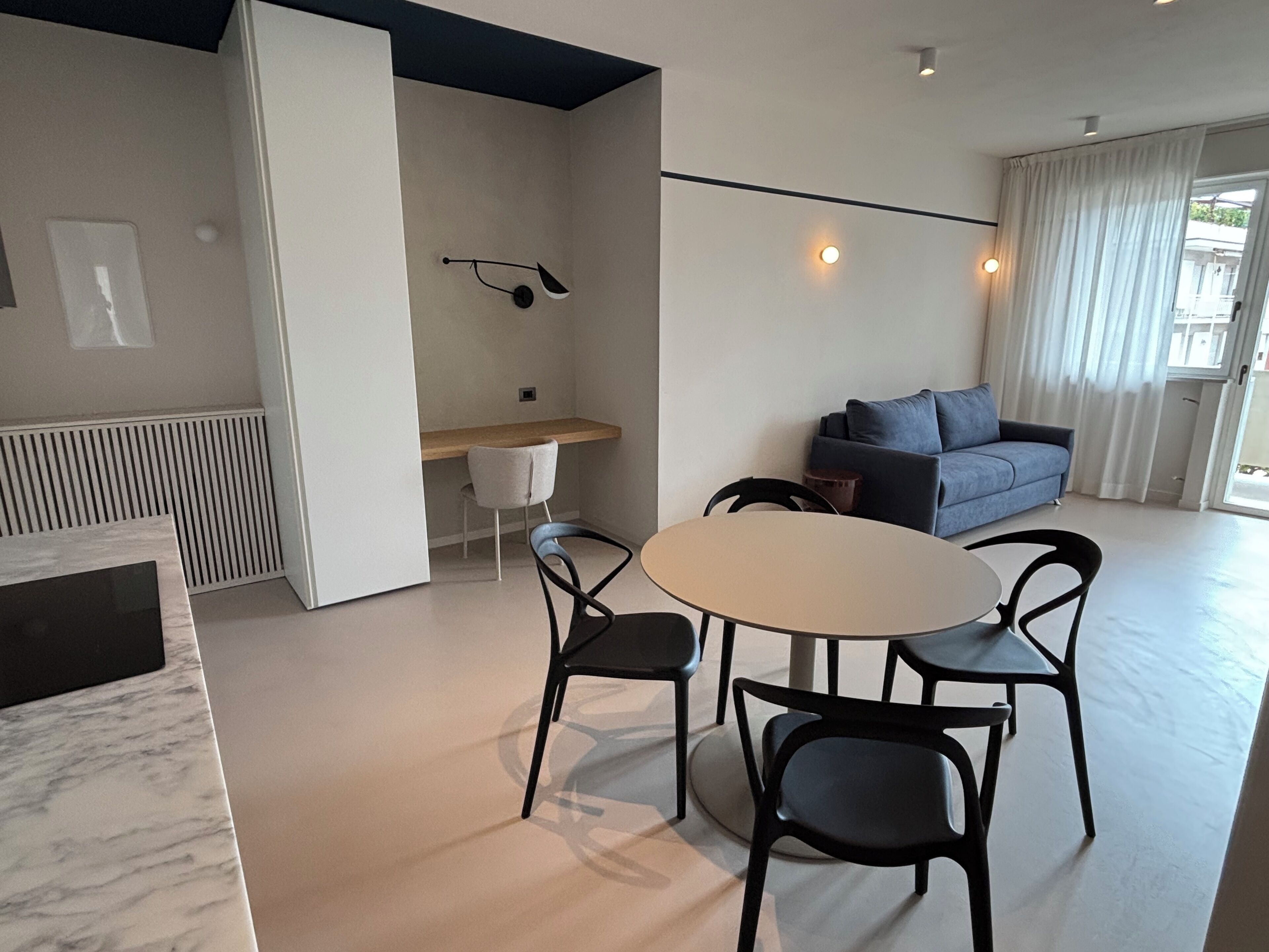 A modern living space with a dining area, a sofa, and a desk.